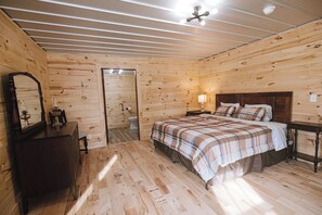 A wooden-paneled bedroom with a bed, dresser, and a mirror.