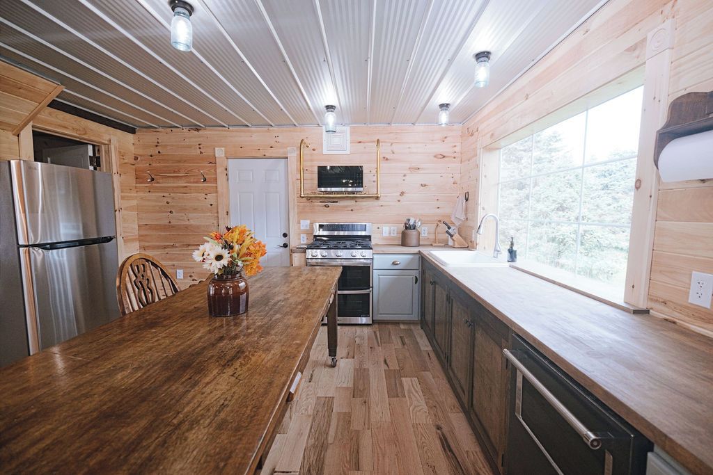 Un interior de madera con cocina, que incluye un refrigerador, estufa y pileta.