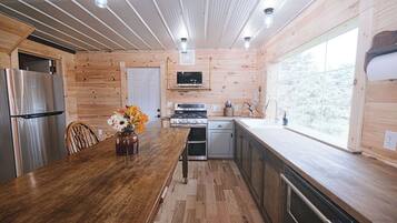 Un interior de madera con cocina, que incluye un refrigerador, estufa y pileta.