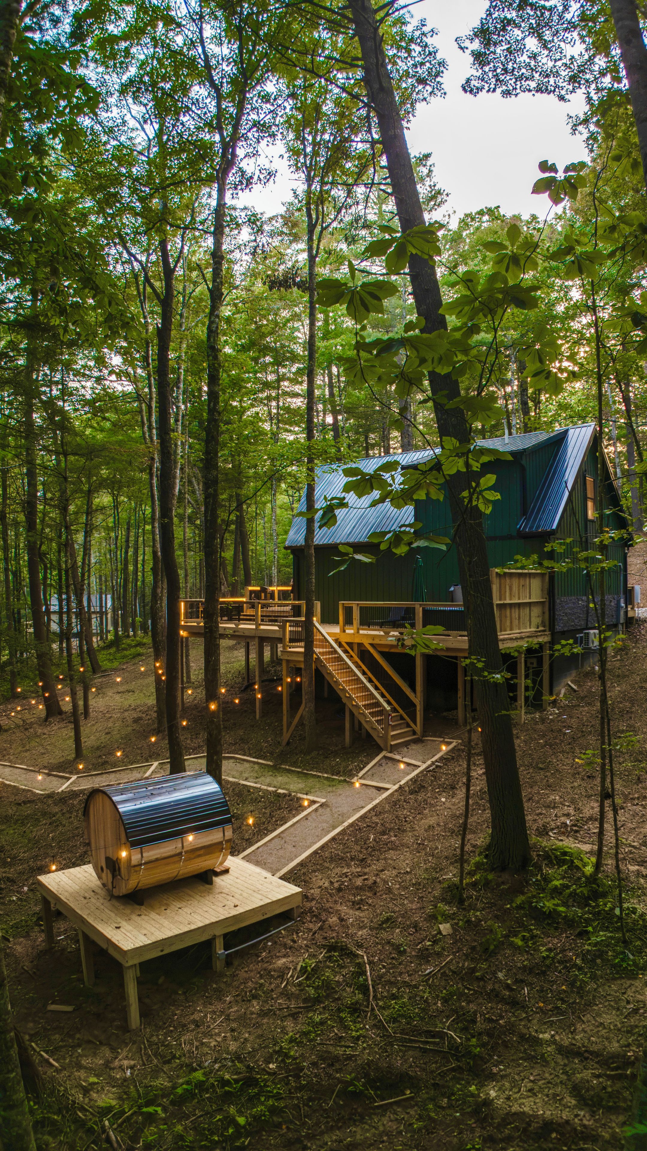 A cabin with a wooden deck and a small wooden structure in a forest.