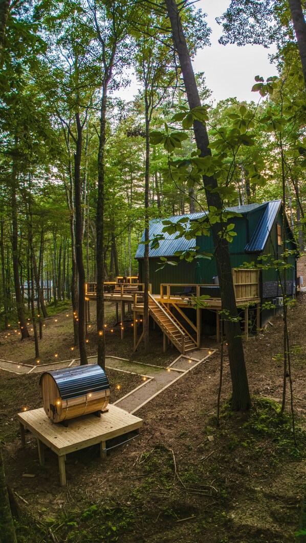 Une cabane dotée d’une terrasse en bois et d’une petite structure en bois, située dans une forêt.