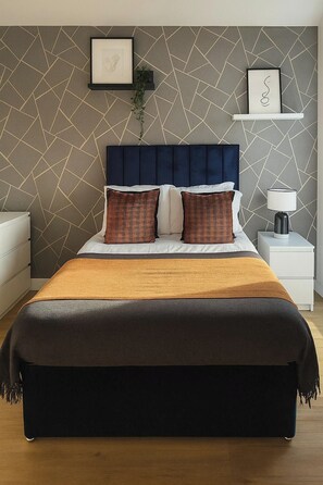 Ein Bett mit dunklem Kopfteil, weißer Bettwäsche und zwei Zierkissen.