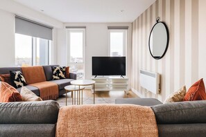 Ein modernes Wohnzimmer mit einer Couch, einem Couchtisch und einem Flachbildfernseher.