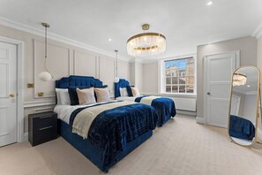 Een slaapkamer met twee bedden, een grote spiegel en een kroonluchter.