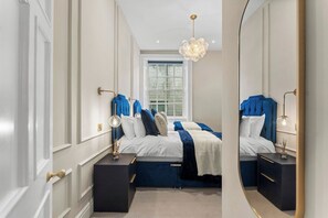 A bedroom with a large bed, bedside tables, a mirror, and a window. - The Bath Grand | Stylish City Centre Stay for 25 (Bath)