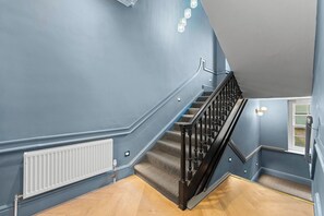 A staircase with a black handrail and carpeted steps leading to a landing. - Luxurious Abode in Central Bath (Bath)