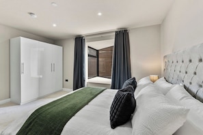 Ein modernes Schlafzimmer mit einem Bett, einem Kleiderschrank und Blick durch ein Fenster.