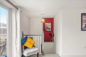 A room with a grey chair, a white curtain, a red wall, and a framed picture. - Chic Bristol Penthouse - Private Rooftop (Bristol)