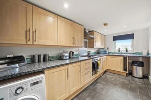 A modern kitchen with wooden cabinets, a built-in oven, and a dishwasher. - Chic Bristol Penthouse - Private Rooftop (Bristol)