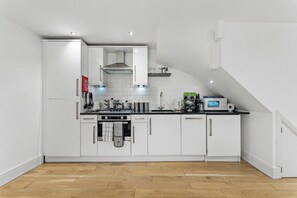 A modern kitchen with white cabinets, a built-in oven, and a microwave. - The Gatsby | Stylish Stay Near Roman Baths (Bath)