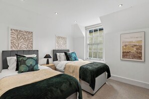 A bedroom with two beds, a window, and artwork on the walls. - The Gatsby | Stylish Stay Near Roman Baths (Bath)