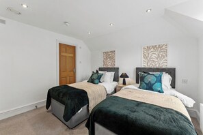 A bedroom with two beds, a wooden door, and a patterned wall. - The Gatsby | Stylish Stay Near Roman Baths (Bath)