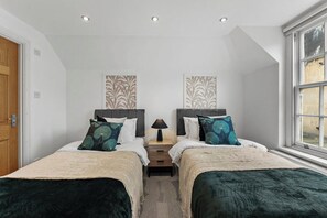 Een slaapkamer met twee bedden, een nachtkastje en een raam.
