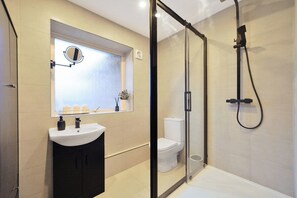Ein modernes Badezimmer mit Duschkabine aus Glas, Waschbecken in Weiß und Toilette.