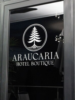 Señal de hotel con logotipo de árbol y el nombre 'ArauCaria Hotel Boutique'.