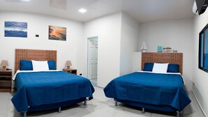 Quarto de hotel com duas camas, cabeceira de madeira, mesa de cabeceira, abajur e ar-condicionado fixado na parede.
