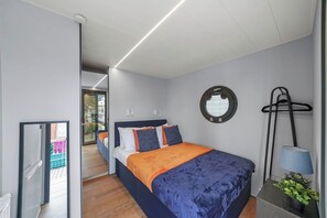 A modern bedroom with a bed, bedside table, and a mirror on the wall.