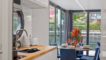 A modern kitchen with a dining area, large windows, and a view of a body of water.