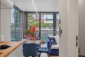 Un comedor moderno con una mesa dispuesta para dos personas, un sofá y vistas a un canal.
