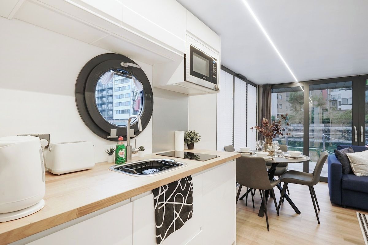 Una cocina moderna con microondas integrado, un lavamanos y una ventana con vistas a la ciudad.