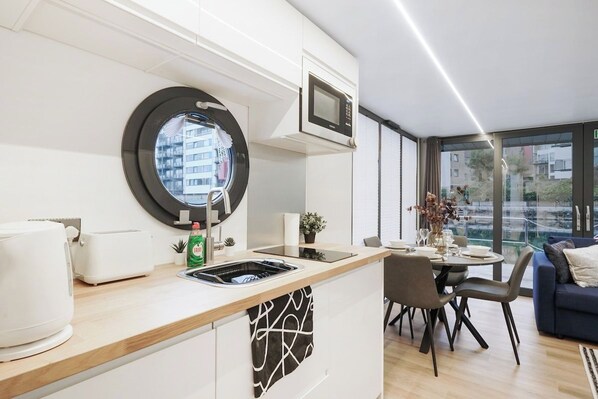 A modern kitchen with a built-in microwave, a sink, and a window overlooking a cityscape.