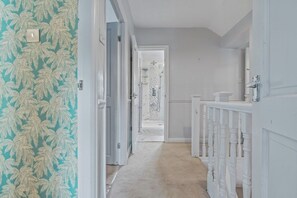 A hallway with a patterned wallpaper, a white door, and a white railing. - Stylish Suburban Escape - Perivale Haven (London)