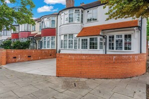 A row of terraced houses with a brick wall and a paved walkway. - Stylish Suburban Escape - Perivale Haven (London)