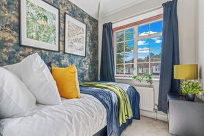 Ein Schlafzimmer mit einem Bett, einem Fenster mit Vorhängen und einer Heizung.