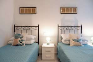 Ein Doppelzimmer mit zwei Betten, jeweils einem Nachttisch und einer Lampe.