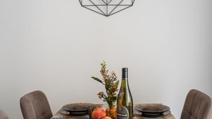 Ett matbord med en väggklocka i geometrisk design, en vas med blommor och en vinflaska.