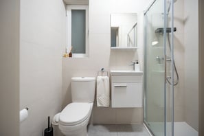 Ein modernes Badezimmer mit Toilette, Waschbecken und einer Duschkabine aus Glas.
