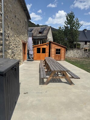 Ein Picknicktisch vor einem Steinhaus mit einer Holztür und einem kleinen Nebengebäude.