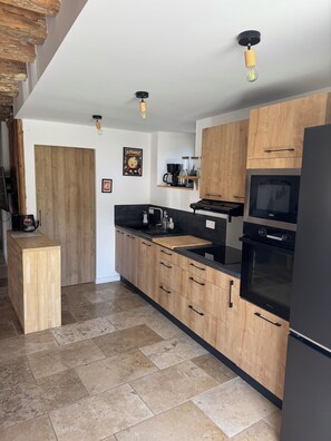 Eine moderne Küche mit Holzausstattung, einem schwarzen Kühlschrank und einem eingebauten Backofen.