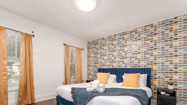 Una camera da letto con un letto, tende, una parete decorata e un tavolino con una pianta.