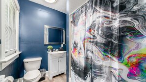 Un bagno con una parete blu, sanitari bianchi e un grande murale astratto.