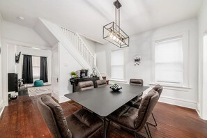 A dining area with a dark table, six chairs, and a chandelier.