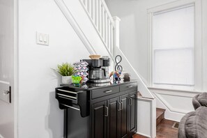 A kitchen area with a coffee maker, a plant, and a decorative item on a black cabinet.