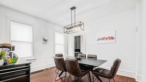 Zona pranzo con tavolo nero, quattro sedie e lampadario.