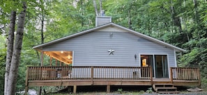 A cabin with a deck, a chimney, and a star decoration. - Secluded 2 BR Mountain Creeksong Cottage with Beautiful Fall Color Views (Burnsville)