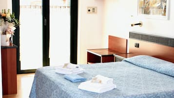 Una habitación de hotel con una cama, un escritorio, una silla, una puerta y una ventana.