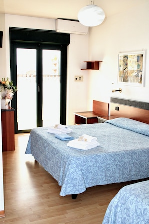 Una habitación de hotel con una cama, un escritorio, una silla, una puerta y una ventana.