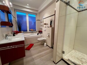 Ein modernes Badezimmer mit Badewanne, Toilette und Dusche.