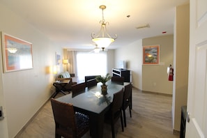 A dining area with a glass table, wicker chairs, a ceiling fan, and wall-mounted artwork. - Enjoy Ocean Views, Tropical Breezes & Breakfast on Your Island Getaway (West Bay)