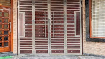 Ein Gebäudeeingang mit einem großen Metallgitter, einer Holztür mit Glasscheiben und einer Ziegelwand.