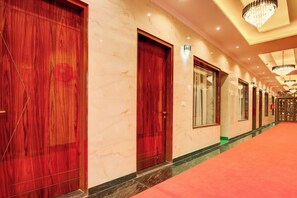 Un pasillo de hotel con paredes de mármol, puertas de madera y alfombra roja.