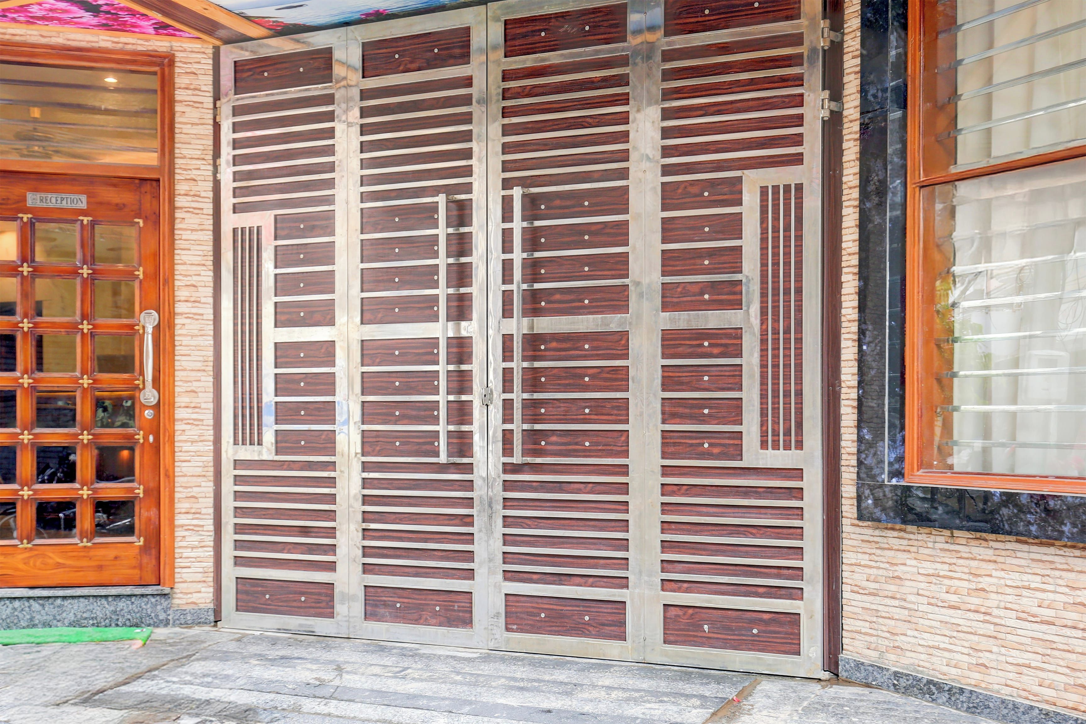 A large, solid metal gate with horizontal slats and a wooden panel design, leading to a reception area with a glass door.