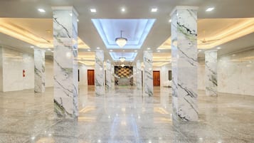 Eine geräumige Lobby mit Marmorsäulen, einer zentralen Treppe und einem Kronleuchter.