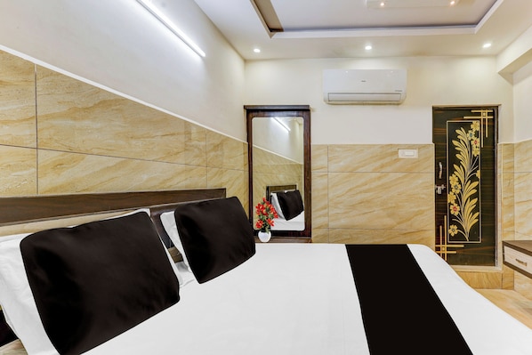 A hotel room with a bed, a mirror, a door with a decorative design, and an air conditioning unit.