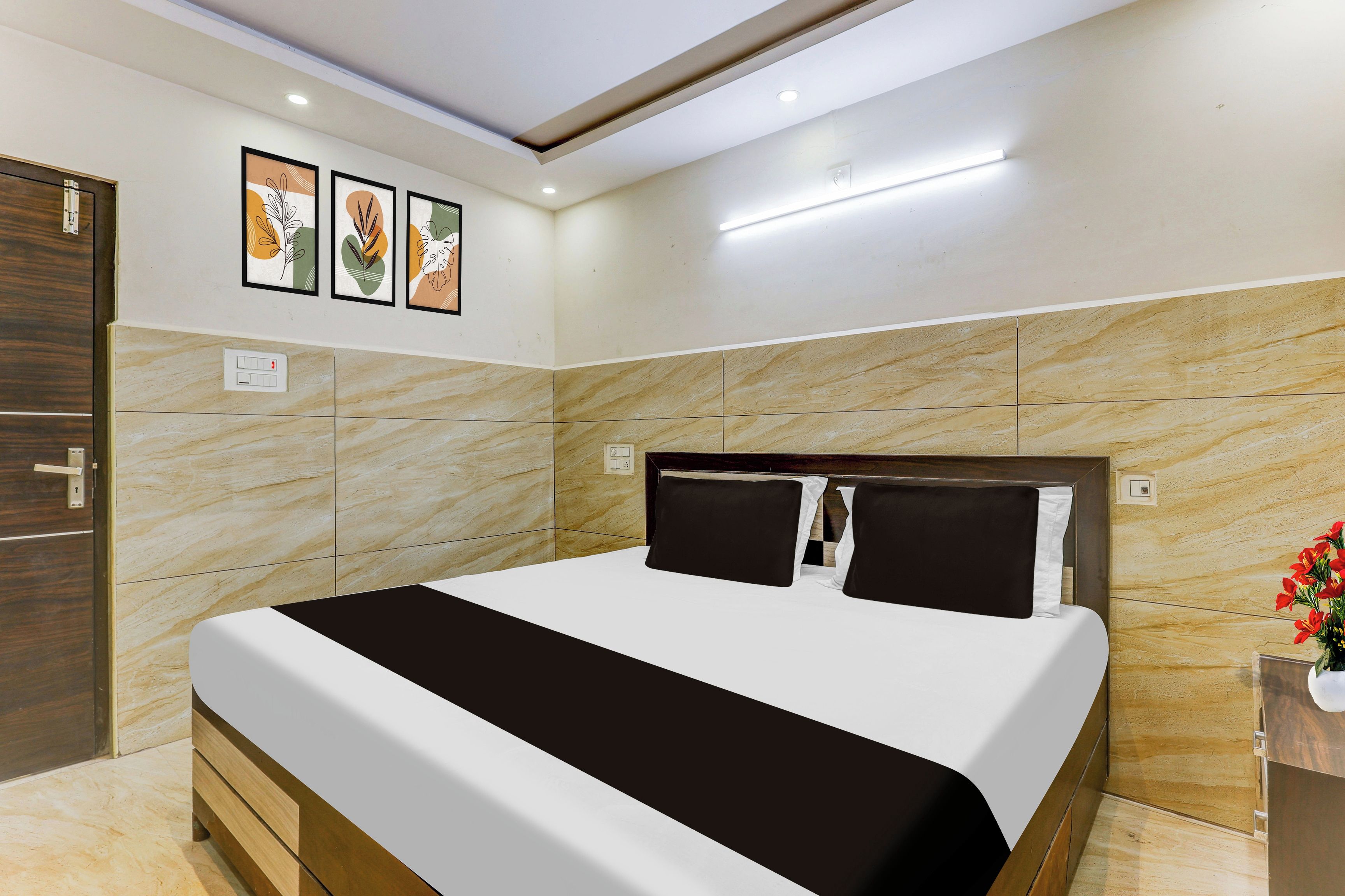 Una habitación de hotel con una cama, una puerta de madera y una pared con tres cuadros.
