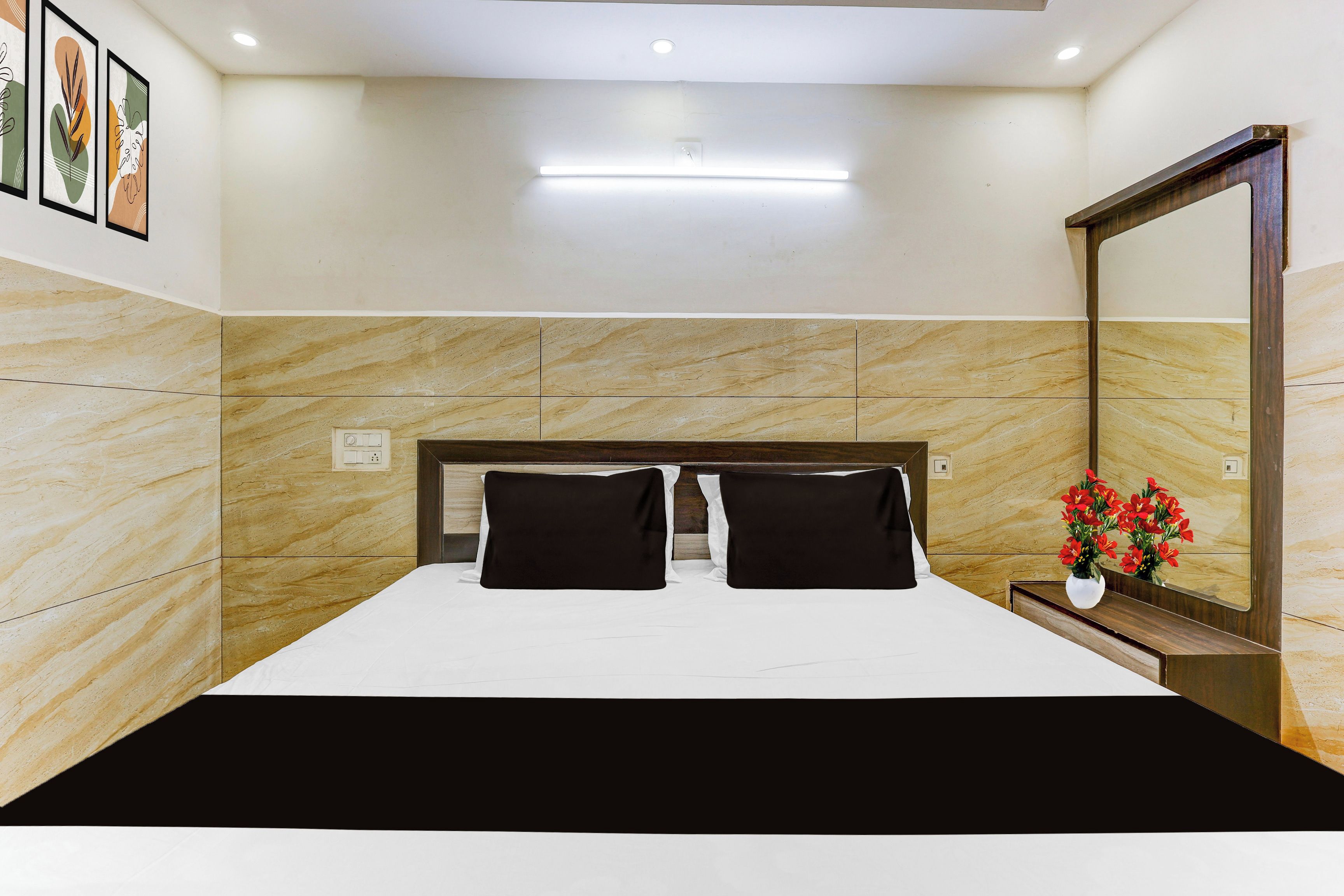 Una habitación de hotel con cama, mesita de noche, espejo y una lámpara de pared.